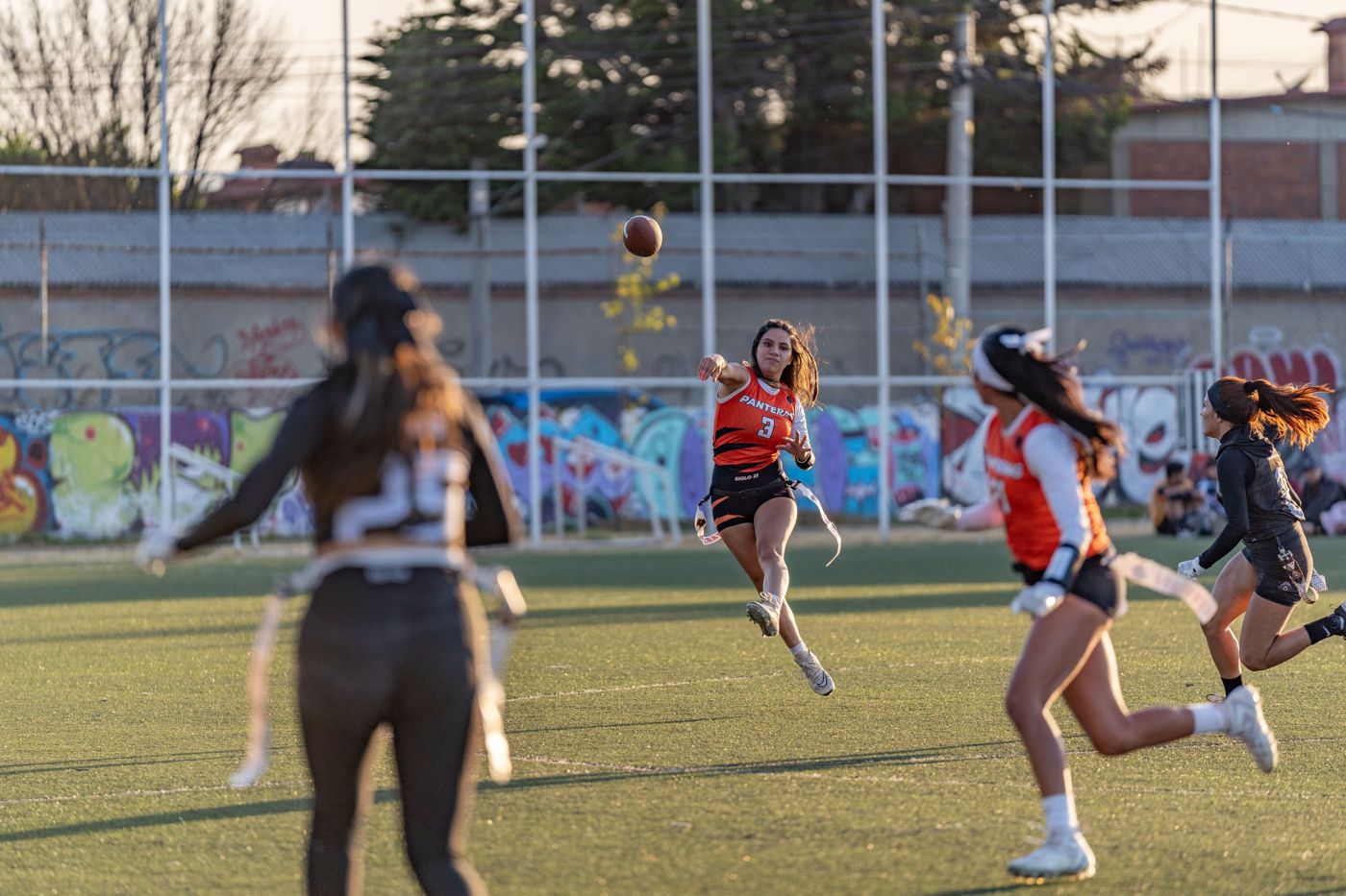 A flag football quarterback throwing a pass at sunset